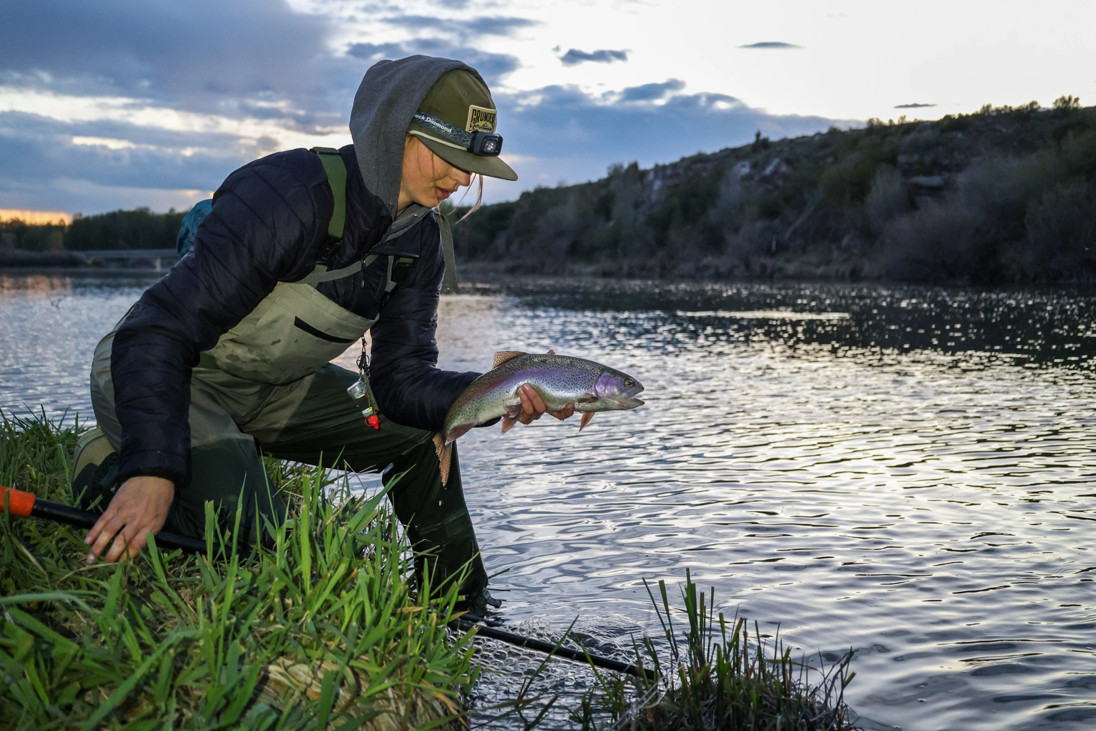 fisherman holding fish next to river